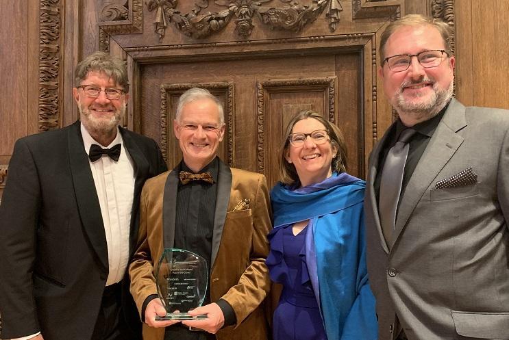 Mark Byford in black tie, Deryck Newland in gold dinner jacket, Kirstie Mathieson in bright blue dress and Andrew Loretto in grey suit holding award