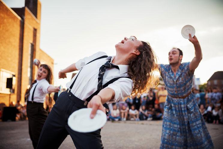 Three dancers performing outside holding cups and saucers