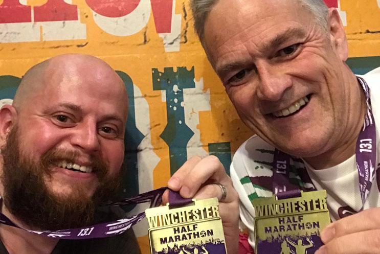 Two exhausted men showing off their medals after their race